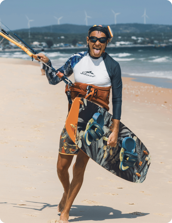 Male kitesurfer walking with a kiteboard and a control bar in his hands