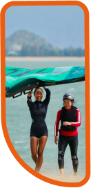 Female walking upwind with a wing giving a class to a female beginner winger