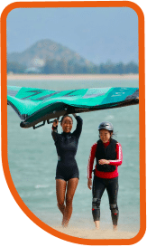 Female walking upwind with a wing giving a class to a female beginner winger