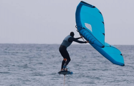 Wing foil lesson 3: Man wing foiling with a wing on a foil board