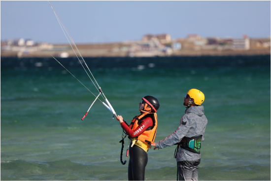 Kitesurfing Lesson 1. Guy flying a kite assisted by a kitesurf instructor.