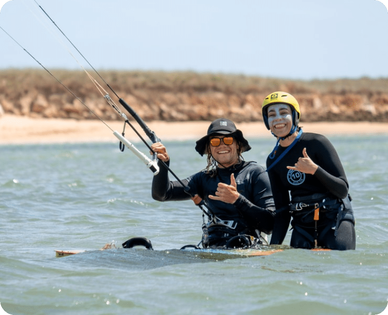 Male holding a kite giving a class to a female beginner kitesurfer smiling