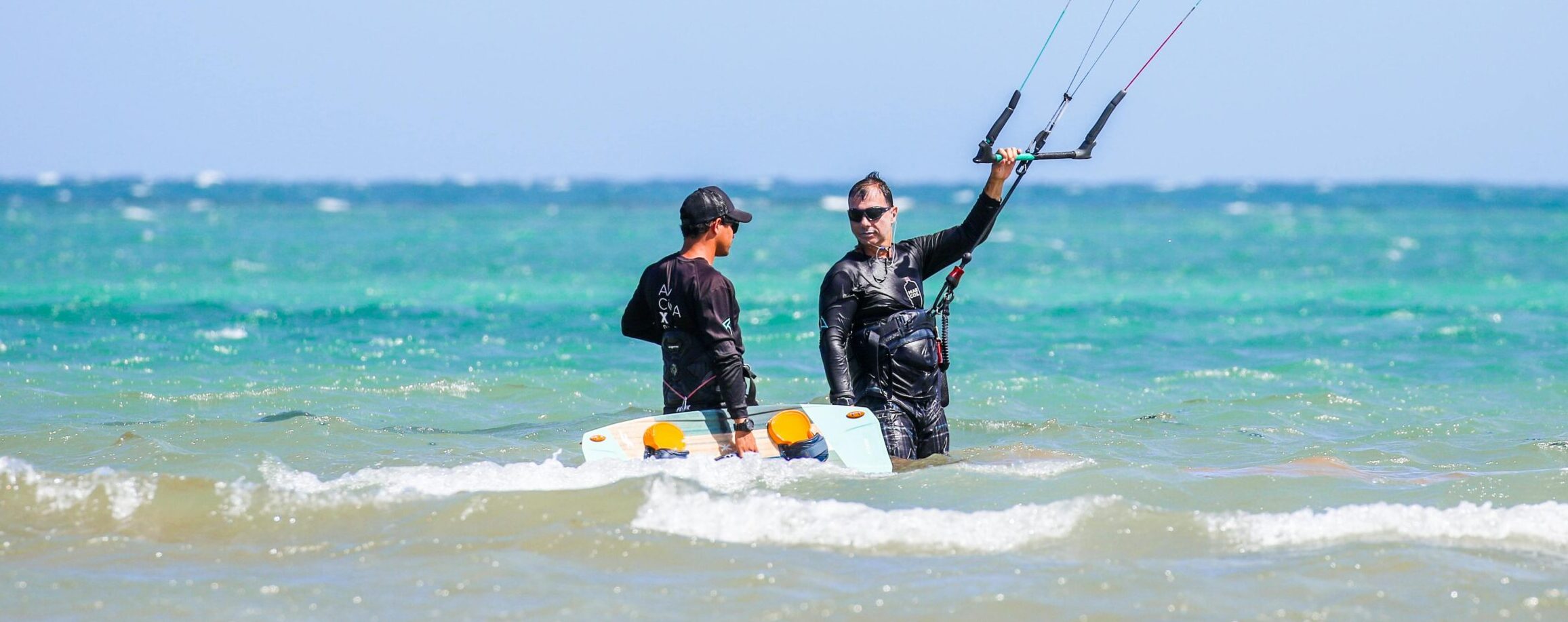 Kitesurfen learnen, Beginner kitesurfers practicing with an instructor on a sunny beach