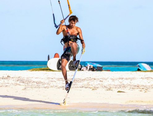 A kiteboarder or kitesurfer performing a trick over flat water